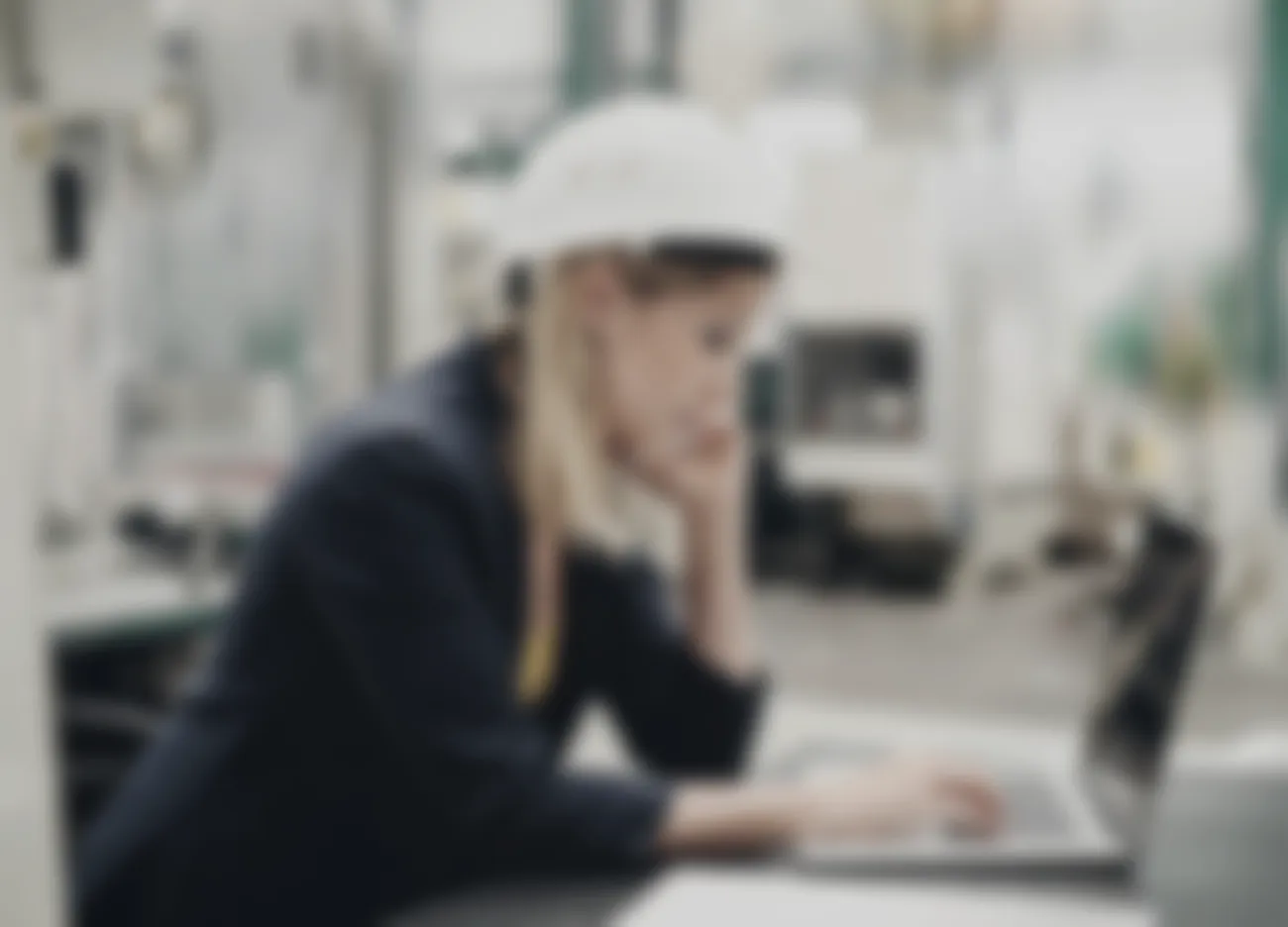 The plant floor behind the engineer, softly out of focus